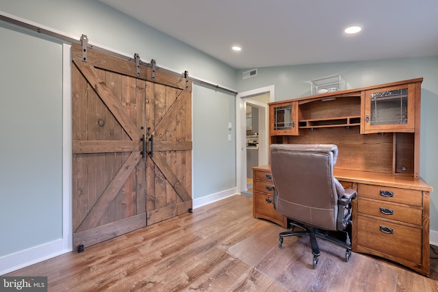 home office with recessed lighting, visible vents, light wood-style flooring, and a barn door