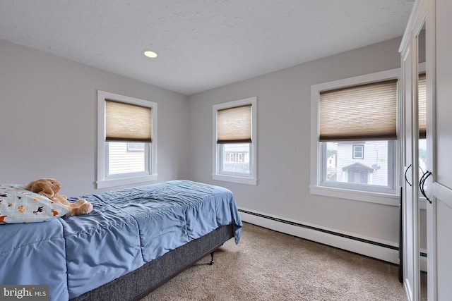 bedroom with baseboard heating, carpet floors, and multiple windows