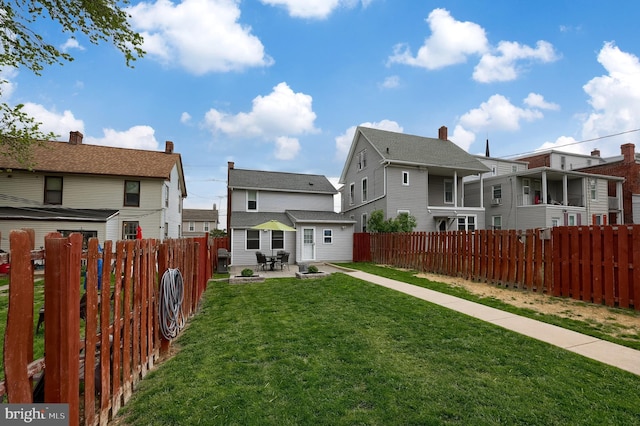 exterior space featuring a residential view, a lawn, a fenced backyard, and a patio area