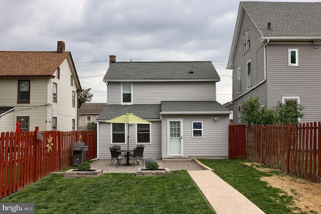 back of property featuring a patio, a yard, a fenced backyard, and roof with shingles