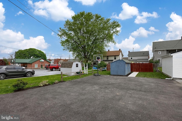 view of front of home featuring fence, an outdoor structure, a shed, and a front lawn