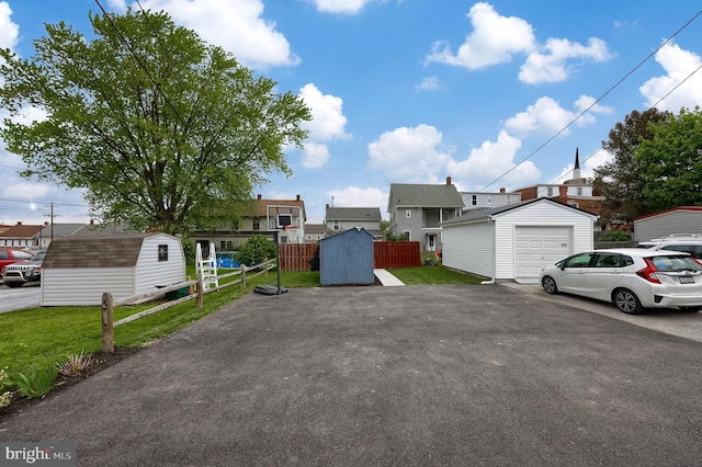 view of property featuring a garage, an outdoor structure, a residential view, driveway, and fence