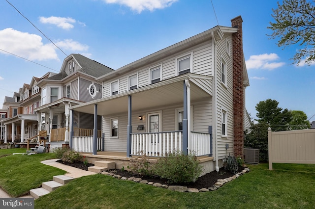 view of front of house with a chimney, covered porch, central air condition unit, and a front lawn