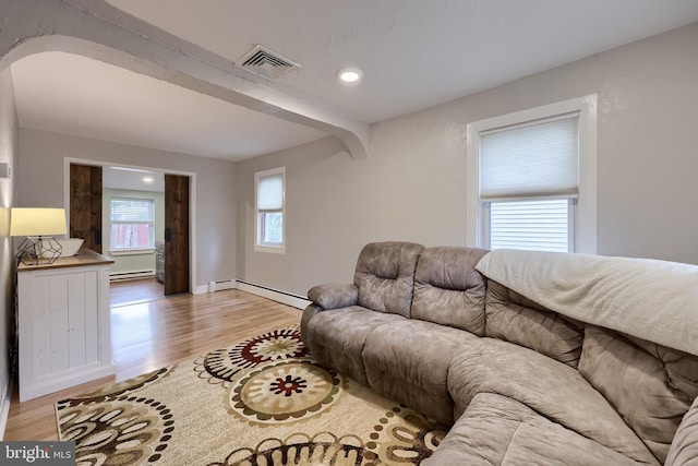 living room featuring baseboard heating, visible vents, a baseboard heating unit, and light wood-style floors