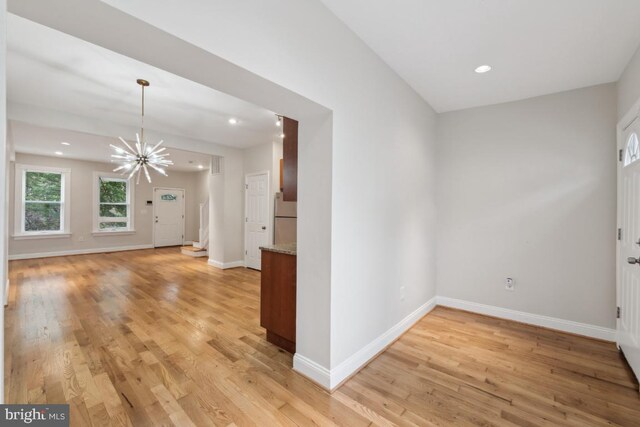 unfurnished room with light wood-type flooring, a chandelier, baseboards, and recessed lighting