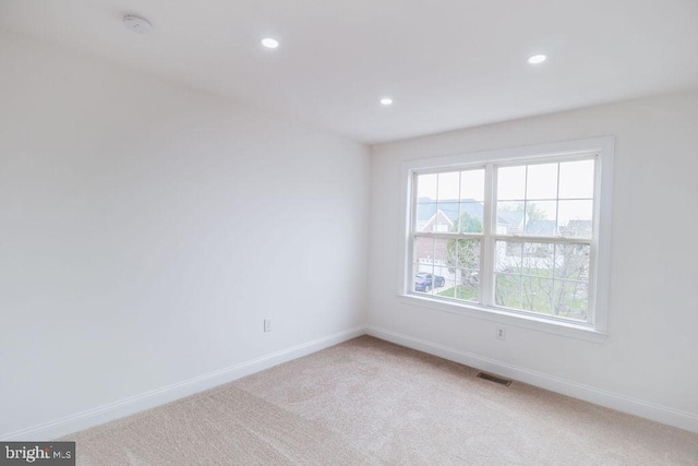 spare room with light colored carpet, baseboards, recessed lighting, and a smoke detector