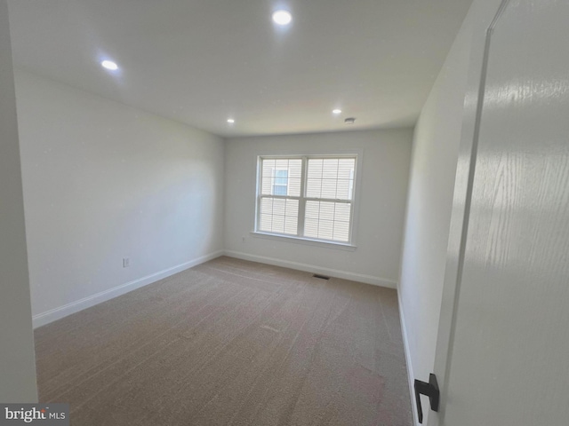 empty room featuring recessed lighting, baseboards, and light carpet