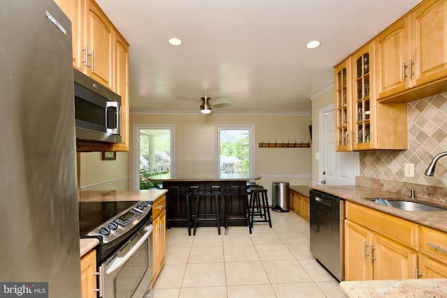 kitchen with light stone countertops, a sink, light tile patterned flooring, tasteful backsplash, and appliances with stainless steel finishes