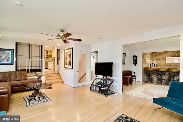 living room featuring wood finished floors, ceiling fan, stairs, and baseboards