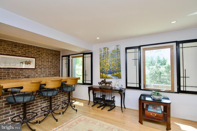 dining space featuring wood finished floors, brick wall, recessed lighting, and baseboards