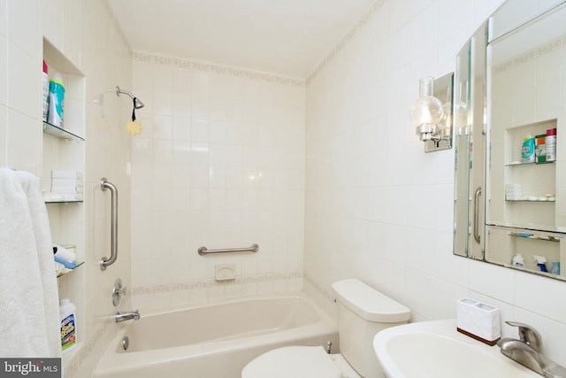 full bath featuring toilet, tile walls, a sink, and tub / shower combination