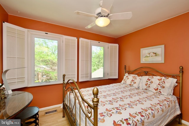 bedroom featuring baseboards, visible vents, wood finished floors, and a ceiling fan