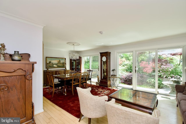 living room featuring visible vents, ornamental molding, an inviting chandelier, and light wood finished floors