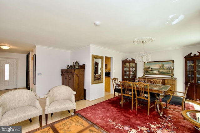 dining area with a chandelier, baseboards, ornamental molding, and wood finished floors