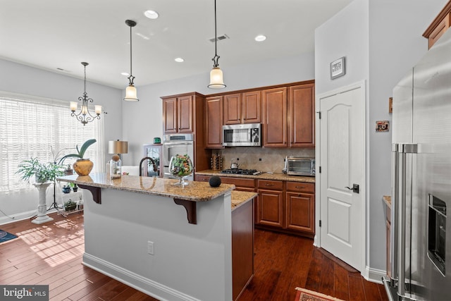 kitchen with visible vents, a breakfast bar, dark wood-style floors, light stone counters, and stainless steel appliances