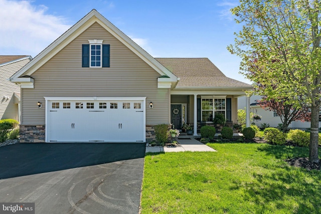 traditional-style house with a porch, stone siding, a front yard, and aphalt driveway
