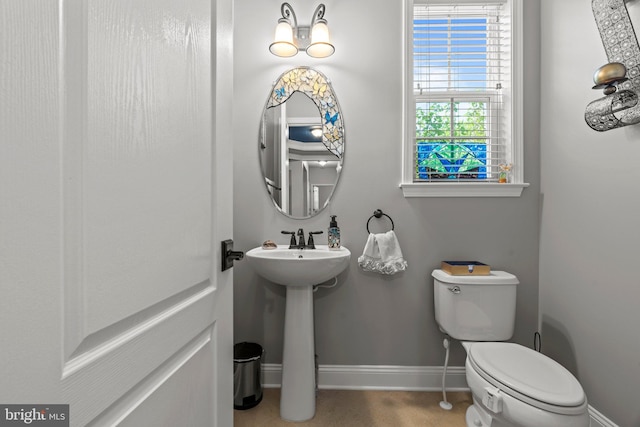half bathroom featuring toilet, baseboards, and a sink