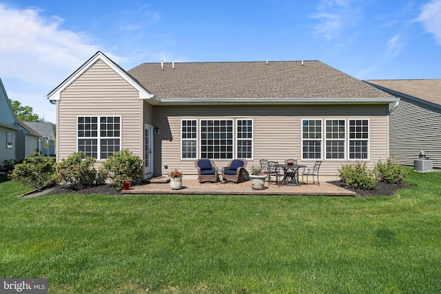 back of property with a shingled roof, a patio area, central air condition unit, and a yard