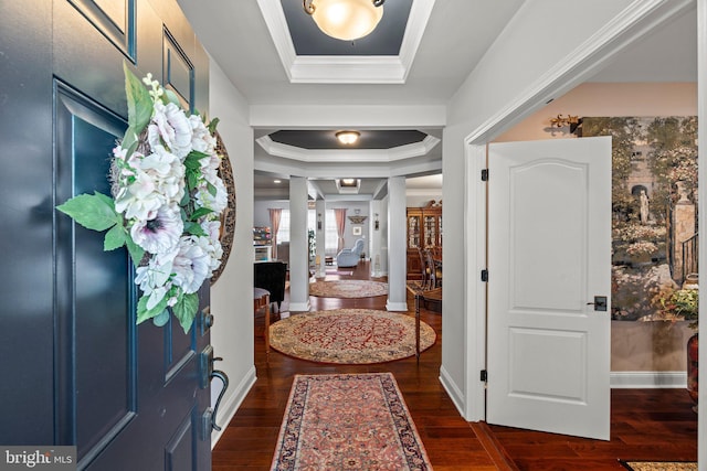 entrance foyer featuring crown molding, a tray ceiling, baseboards, and dark wood-type flooring