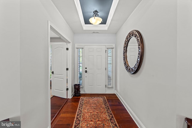 foyer featuring wood-type flooring, a raised ceiling, baseboards, and visible vents