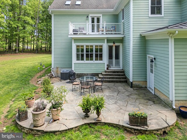 back of property with central AC, entry steps, a patio area, a balcony, and a yard