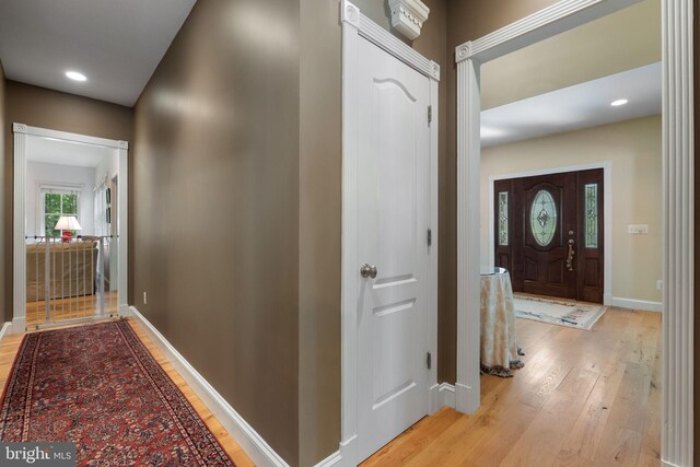 corridor with baseboards, recessed lighting, and light wood finished floors