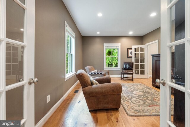 sitting room with visible vents, wood finished floors, baseboards, recessed lighting, and french doors