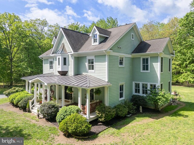 back of property featuring a lawn, roof with shingles, a standing seam roof, and a porch