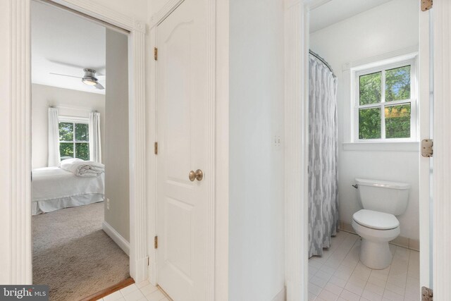 full bathroom with toilet, ensuite bathroom, baseboards, a shower with shower curtain, and tile patterned floors