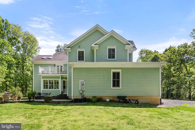 back of house with a lawn and a balcony