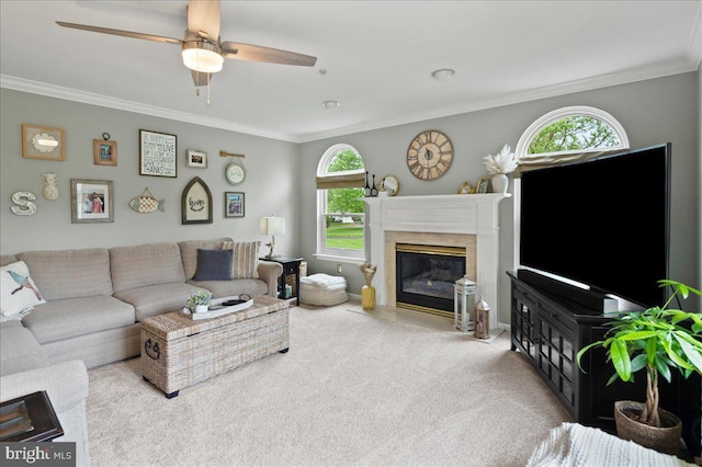 living area with carpet flooring, ornamental molding, a premium fireplace, a ceiling fan, and baseboards