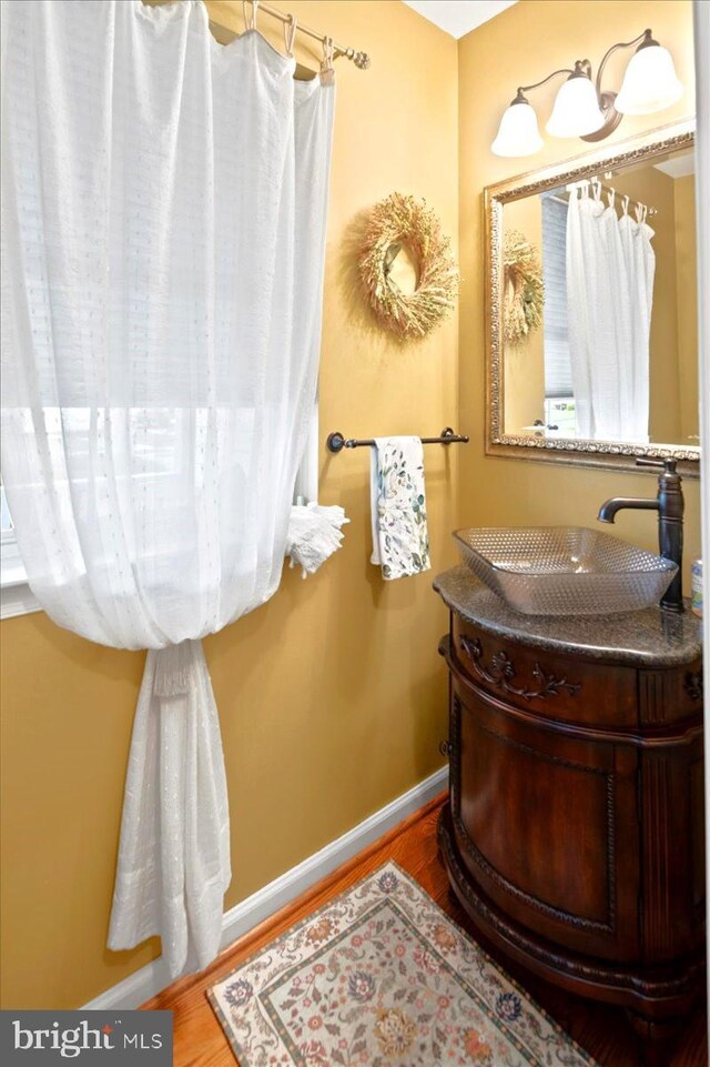 bathroom featuring baseboards, wood finished floors, and vanity