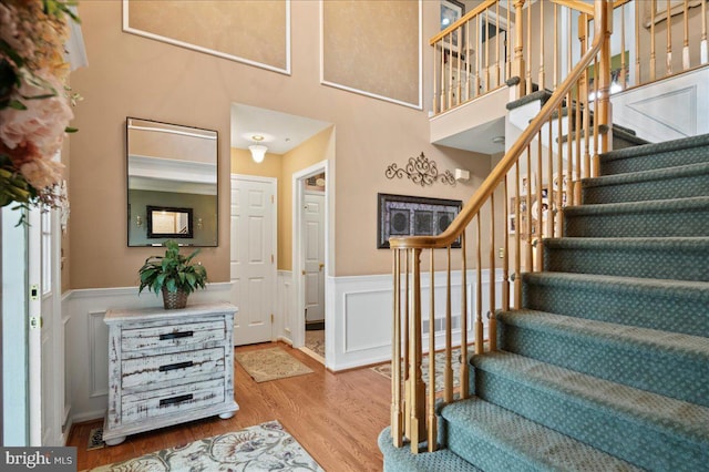 stairs with a wainscoted wall, wood finished floors, and a decorative wall