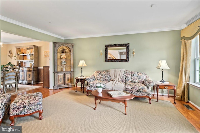 living room featuring ornamental molding, wood finished floors, and baseboards