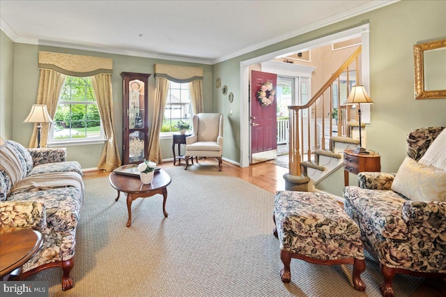 living room with baseboards, wood finished floors, ornamental molding, and stairway