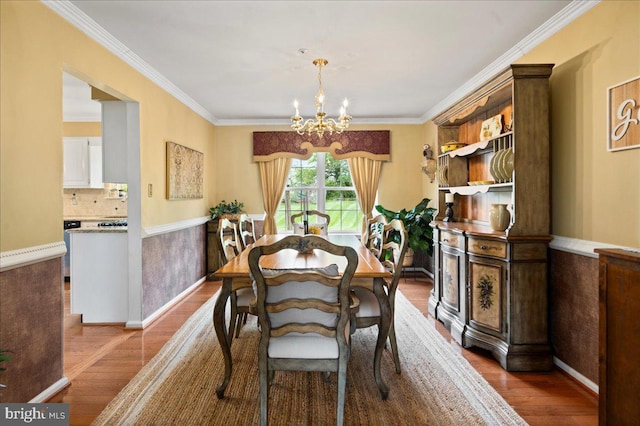 dining area featuring wood finished floors, a chandelier, ornamental molding, and baseboards