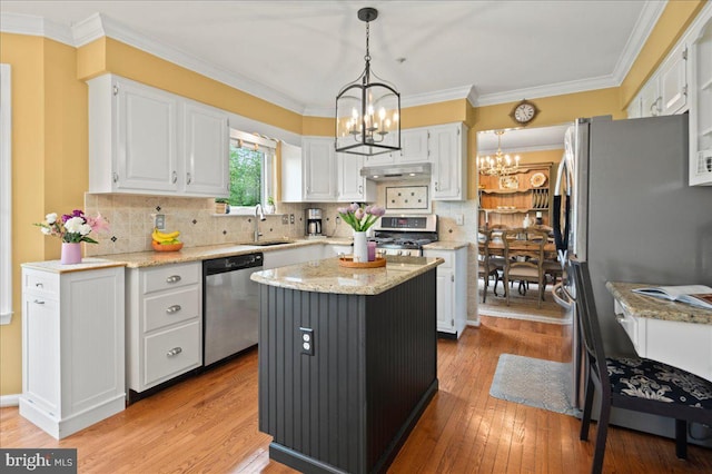 kitchen featuring stainless steel appliances, a chandelier, white cabinetry, a sink, and under cabinet range hood