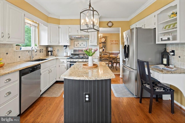 kitchen with appliances with stainless steel finishes, a sink, under cabinet range hood, a kitchen island, and white cabinetry
