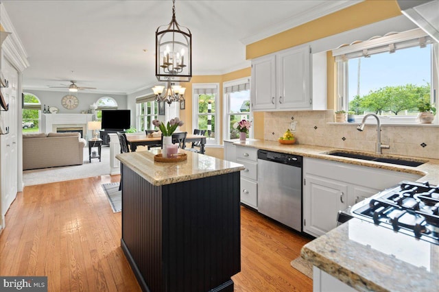 kitchen featuring dishwasher, a sink, a fireplace, ceiling fan, and a center island