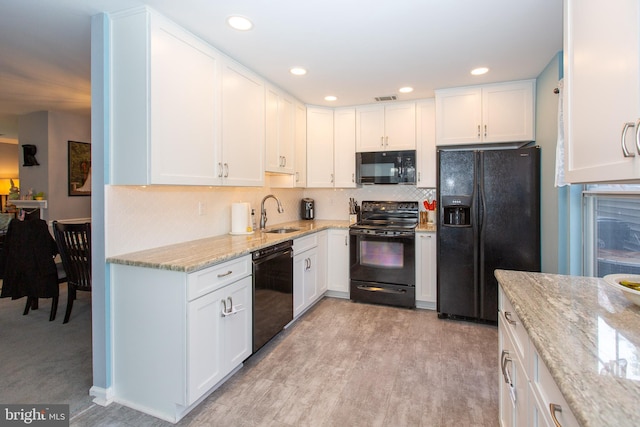 kitchen with black appliances, a sink, light stone countertops, white cabinets, and decorative backsplash