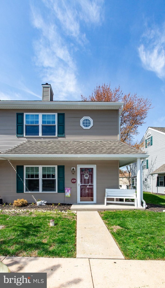 view of front of property featuring a porch, a front lawn, and a chimney