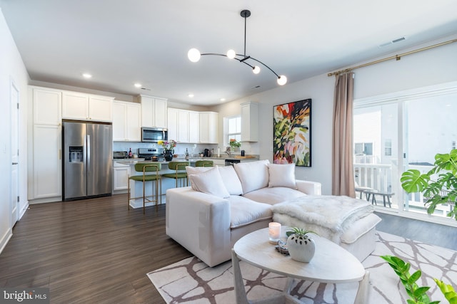 living area featuring visible vents, recessed lighting, dark wood finished floors, and a chandelier