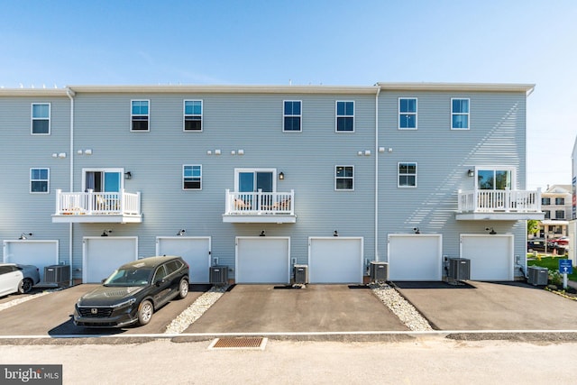 back of house with a garage, central air condition unit, and driveway