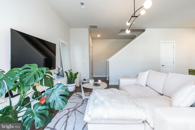 living area with visible vents, baseboards, wood finished floors, and stairway