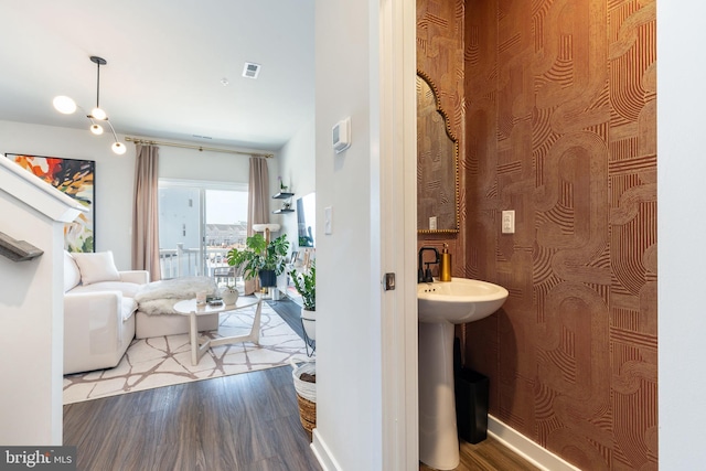 hall with a sink, visible vents, and wood finished floors