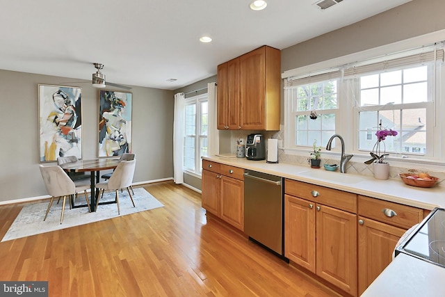 kitchen with light wood-type flooring, a sink, dishwasher, and a wealth of natural light