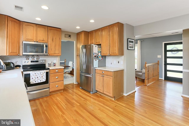 kitchen featuring visible vents, tasteful backsplash, light countertops, stainless steel appliances, and light wood-style flooring