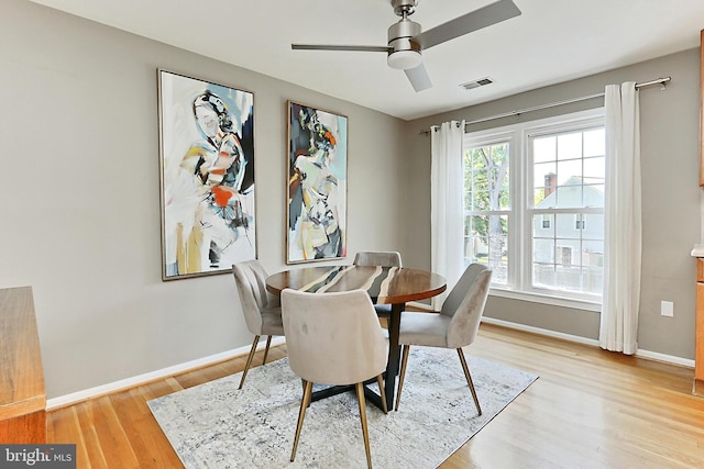 dining space featuring baseboards, visible vents, ceiling fan, and light wood-type flooring