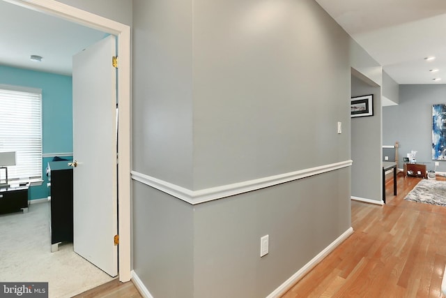 hall with baseboards and light wood finished floors