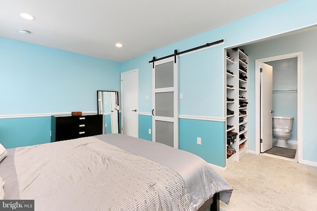 bedroom with carpet flooring, recessed lighting, a barn door, and ensuite bath